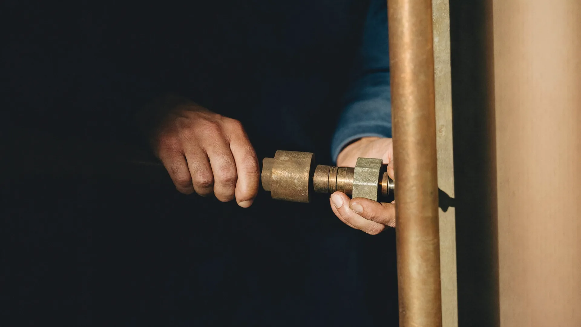 Installateur verpresst eine Rohrverbindung im warmen Werkstattlicht